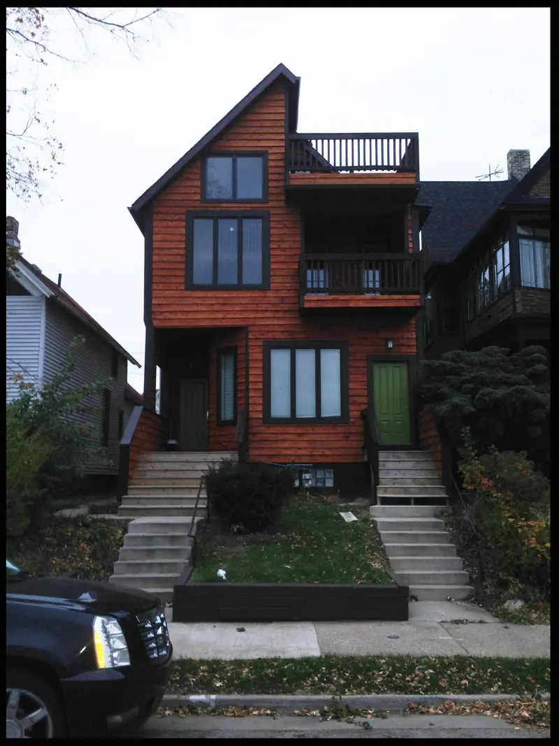 The Glover house after: a modern cedar clad house with two balconies and a green front door