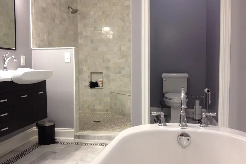 A marble tiled bathroom with a glass shower and a soaking tub