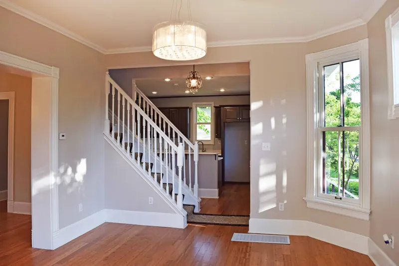An entry with a white staircase, hardwood floors and a drum chandelier